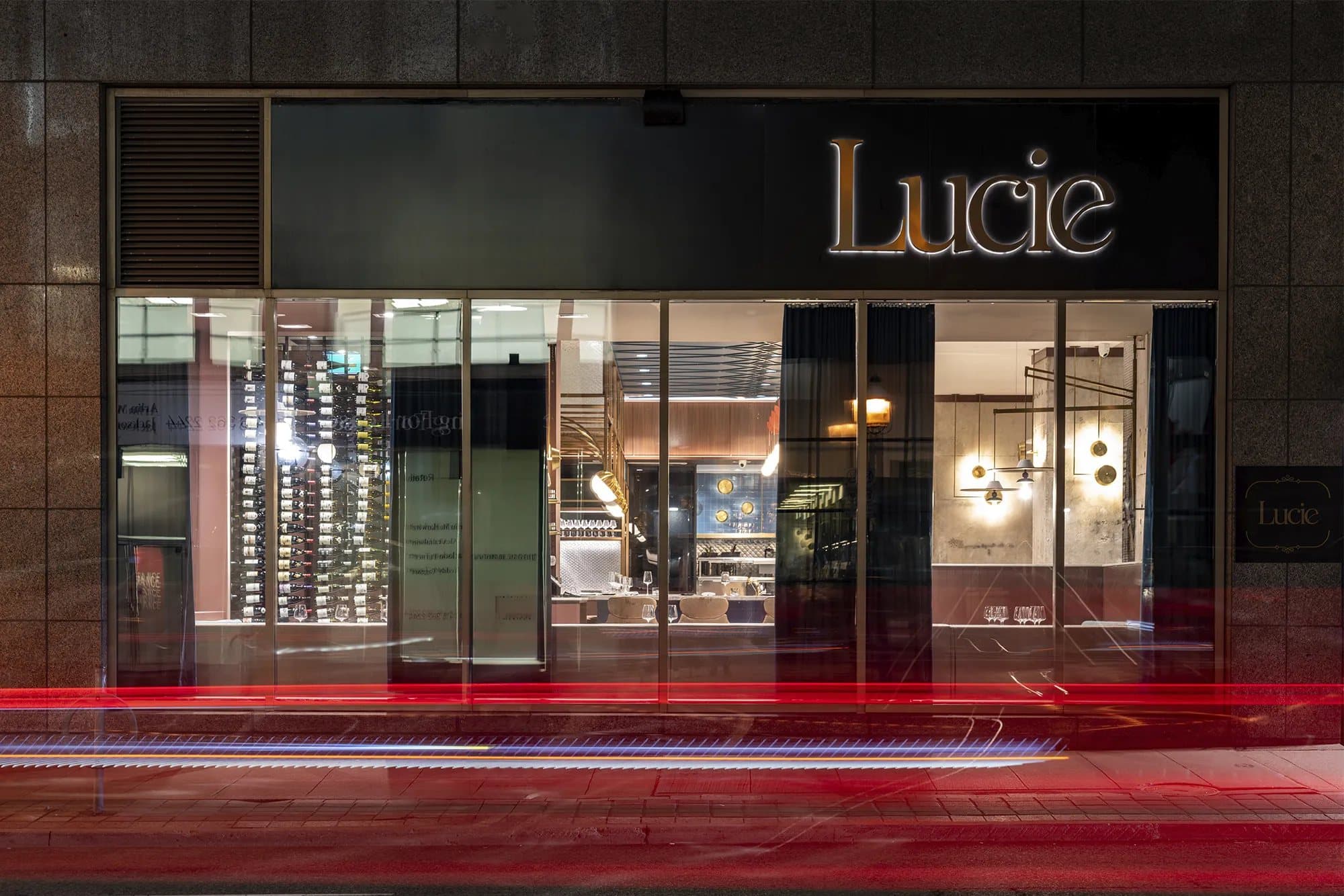 Restaurant Lucie's lit sign and front windows on a Toronto street at night